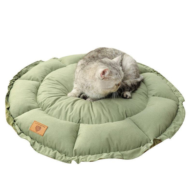 Green calming pet bed with a kitten sleeping soundly.
